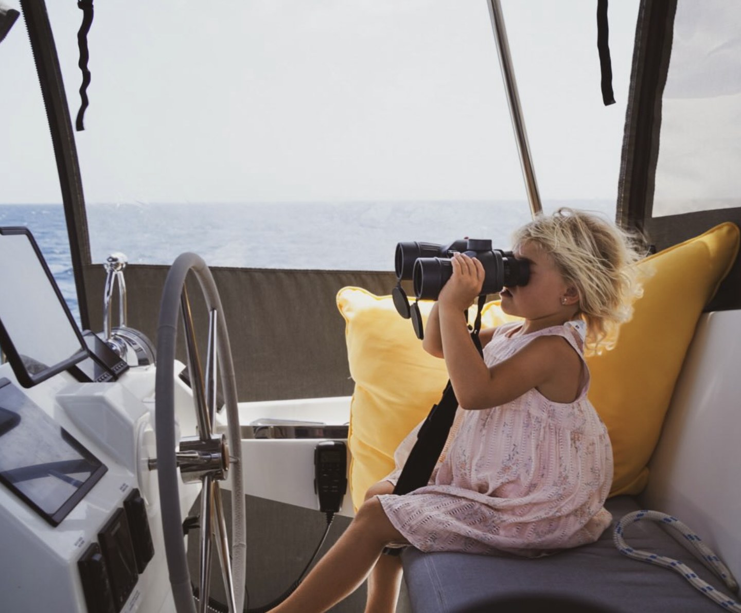 A child using binoculars at the helm.