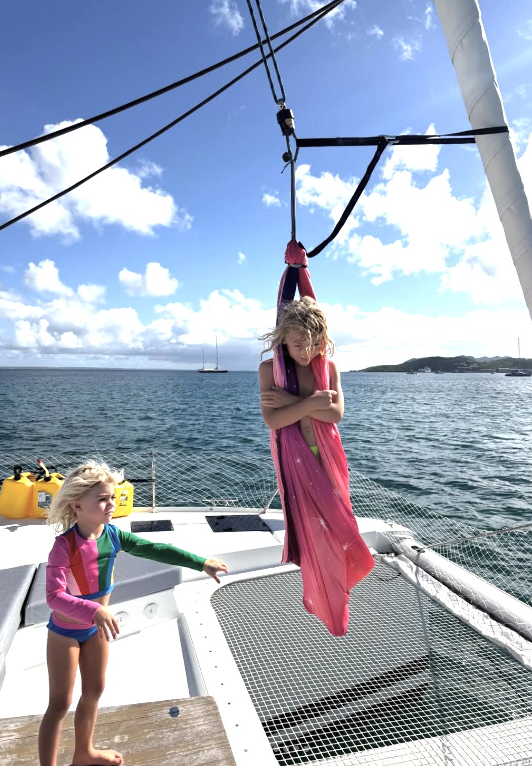 A child playing on the catamaran with the sea behind.