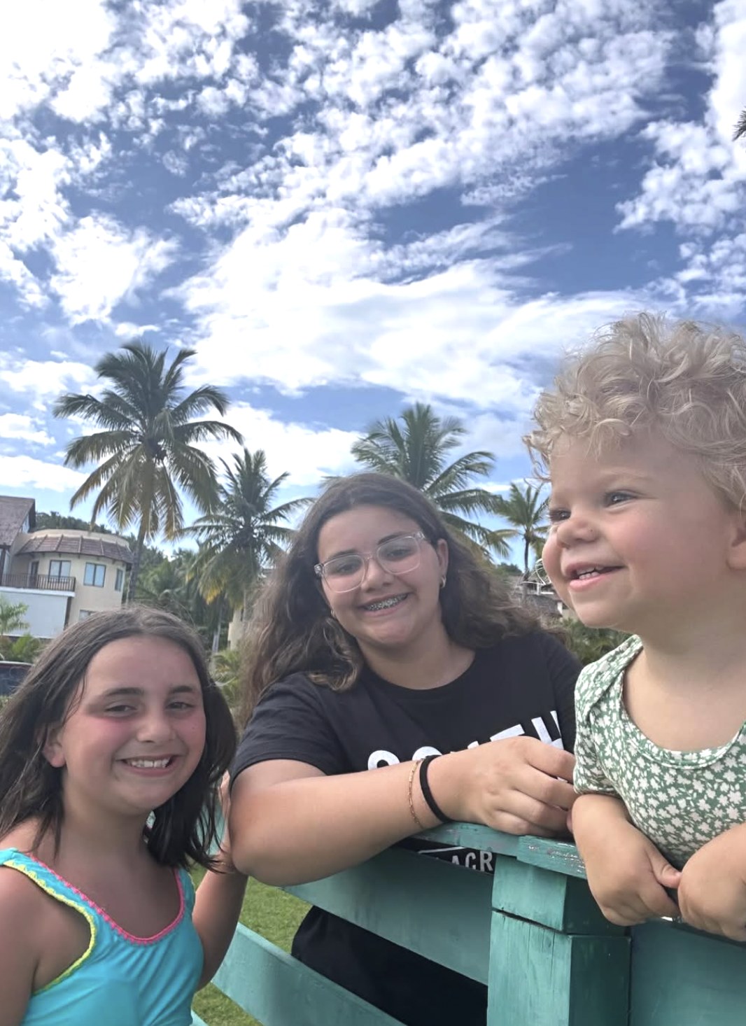 Three children smiling during a tropical shore outing.